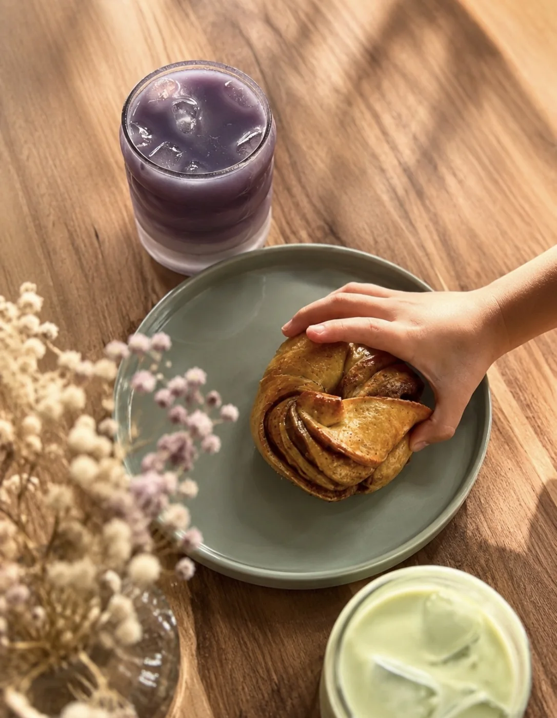 La main d'un enfant tenant un verre violet et une brioche
