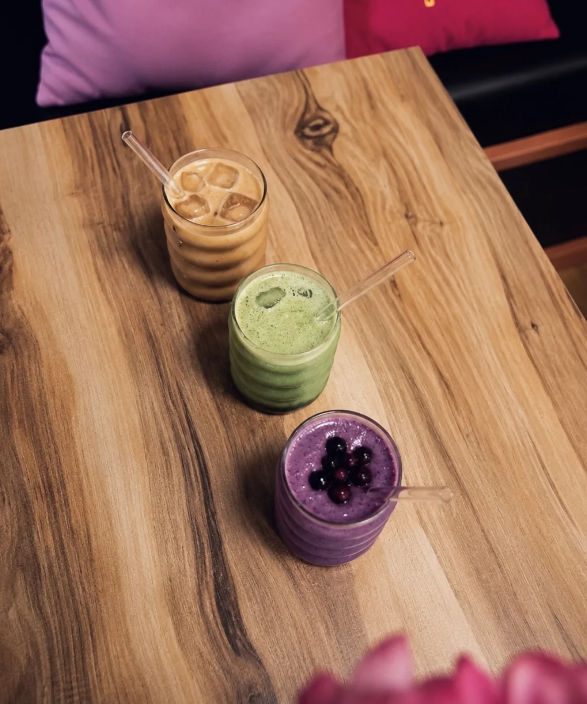 Trois boissons colorées alignées sur une table en bois